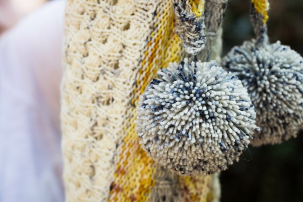 Up close detail of pom poms from knitted shawl