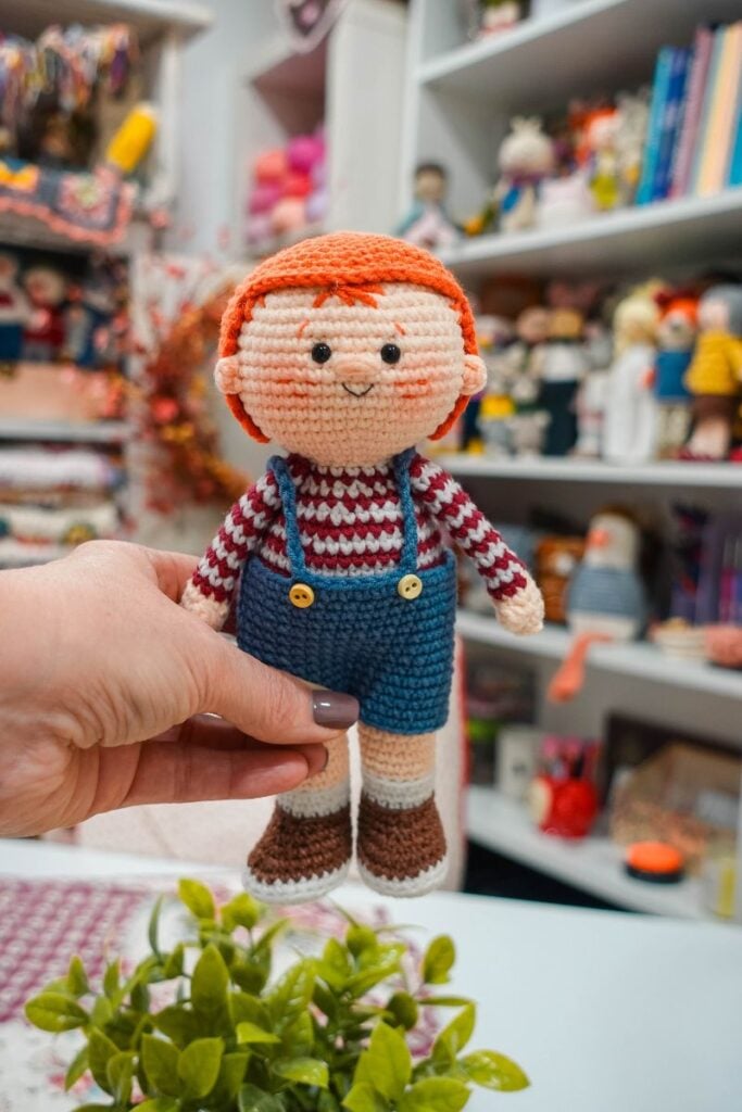 Handmade crochet boy doll with red hair, blue overalls, and brown shoes